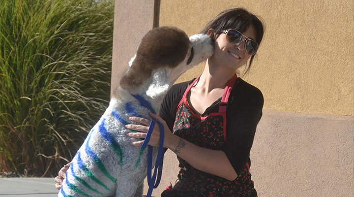 Picture of Samantha with a dog outside of Paw Spa after a groom and color.